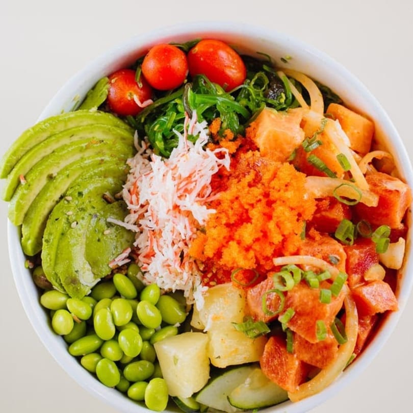 A vibrant Poke Bowl with tuna, salmon, avocado, edamame, crab, roe, and cherry tomatoes.