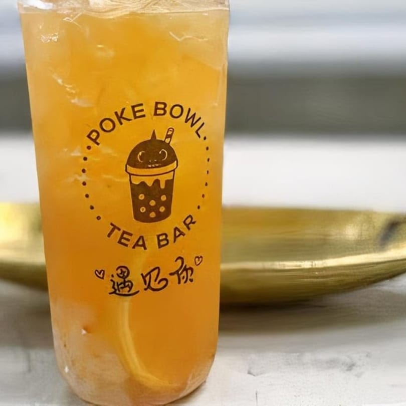 Iced tea with the Poke Bowl Tea Bar logo on a white surface with a gold tray.