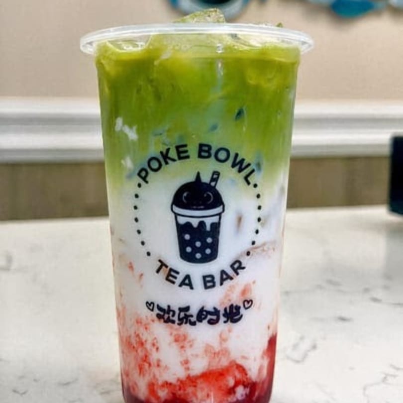 A vibrant layered drink from Poke Bowl Tea Bar with green, white, and red sections.