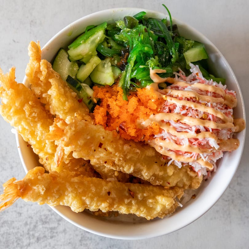 Poke Bowl with crispy tempura shrimp, crab meat, orange roe, seaweed, and cucumber.