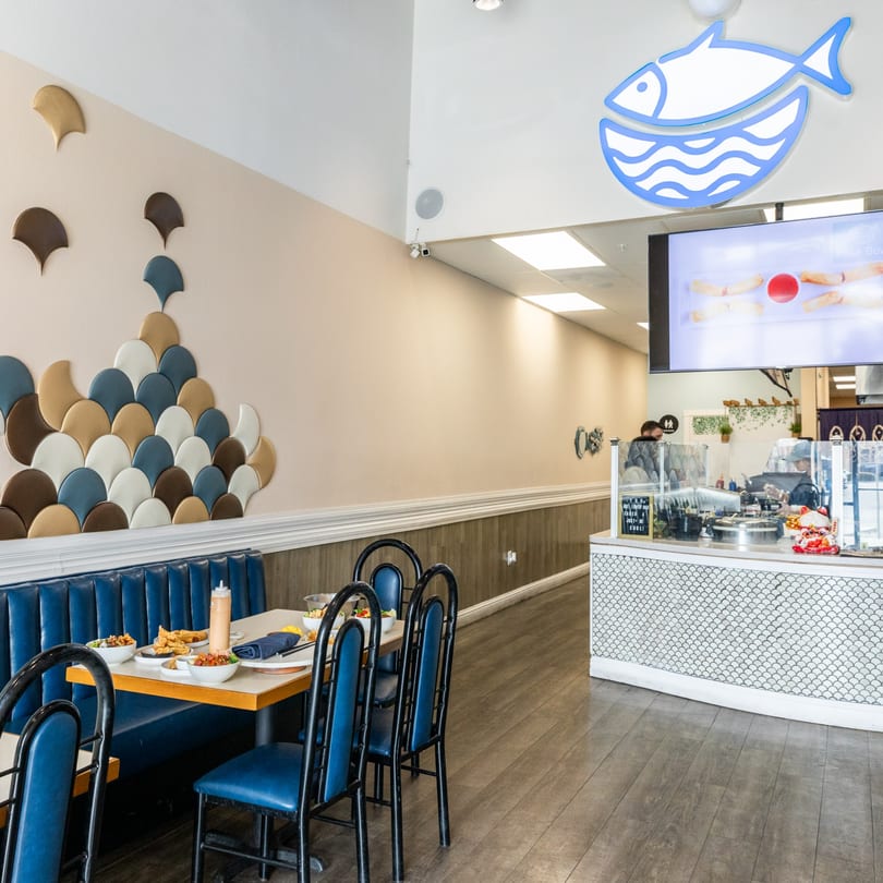 Interior of Poke Bowl restaurant with blue booths, tables with food, and a service counter.